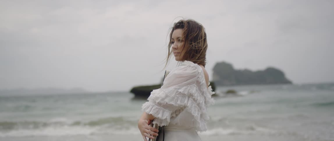 A woman looks out over the water on the beach