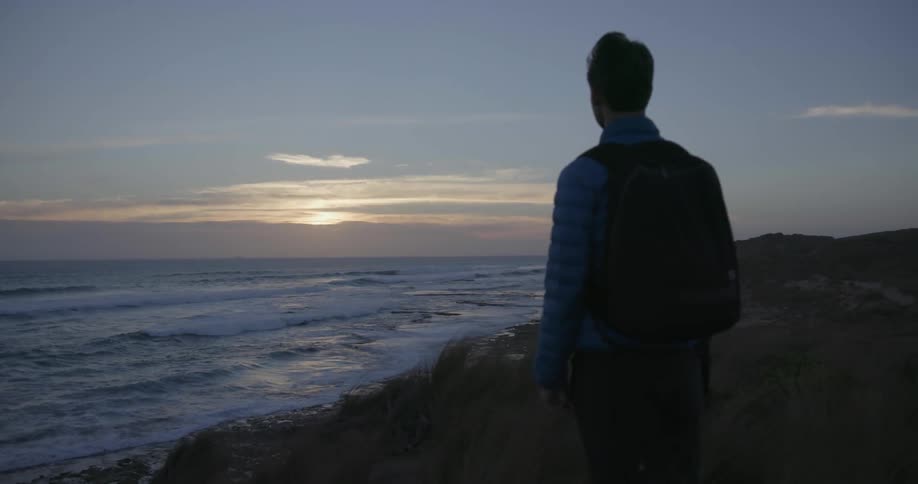 A man stands by the shore at dawn