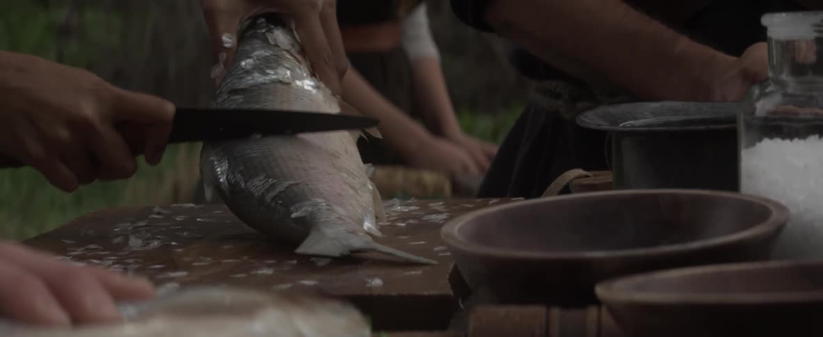 A chef cuts the scales off of a fish