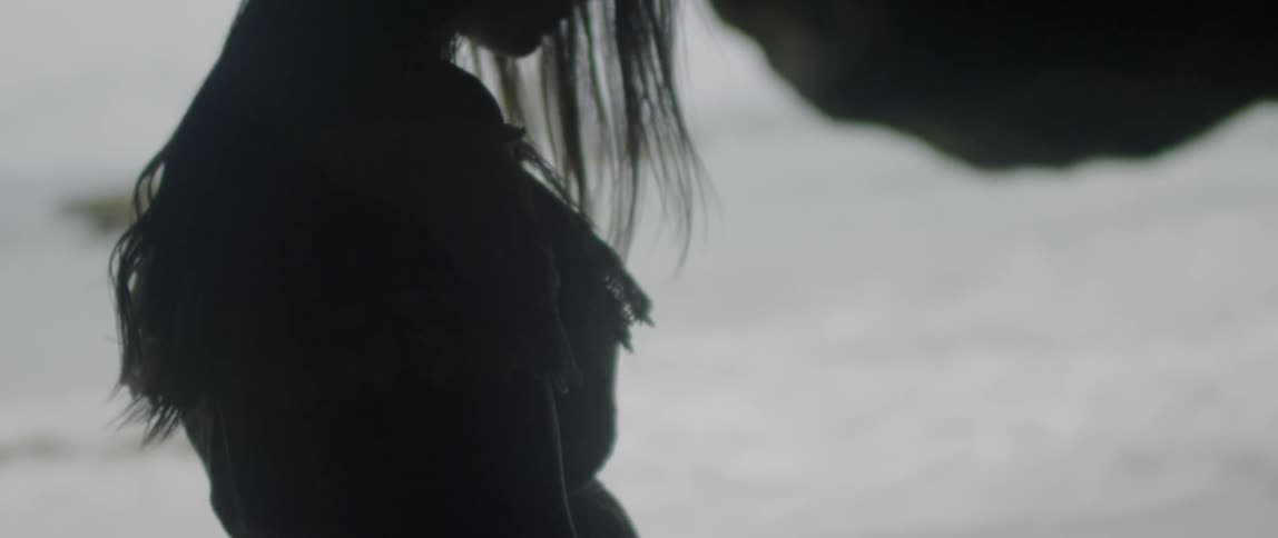 A woman stands outside on a beach