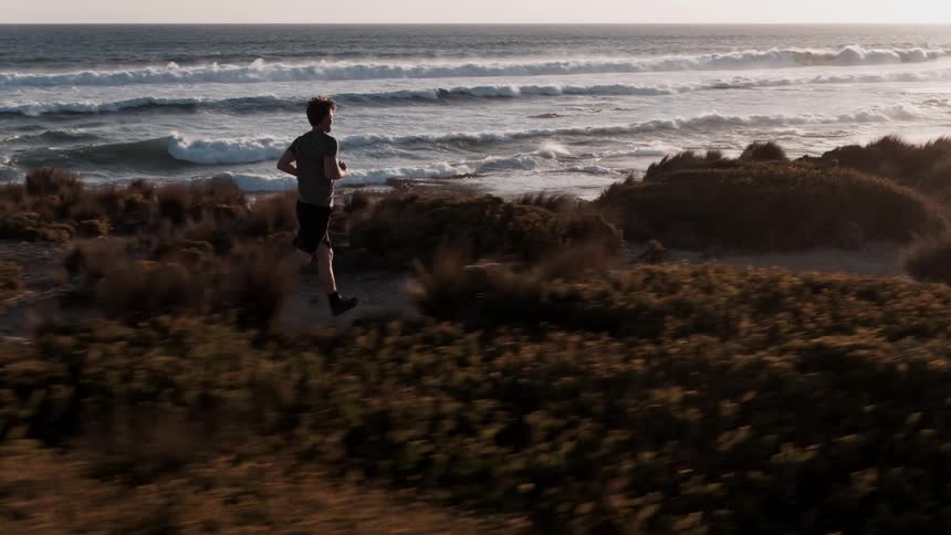 A man jogging at the beach with crashing waves in the background