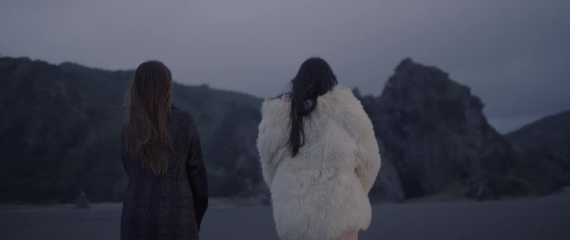 Two women walk outdoors wearing heavy coats