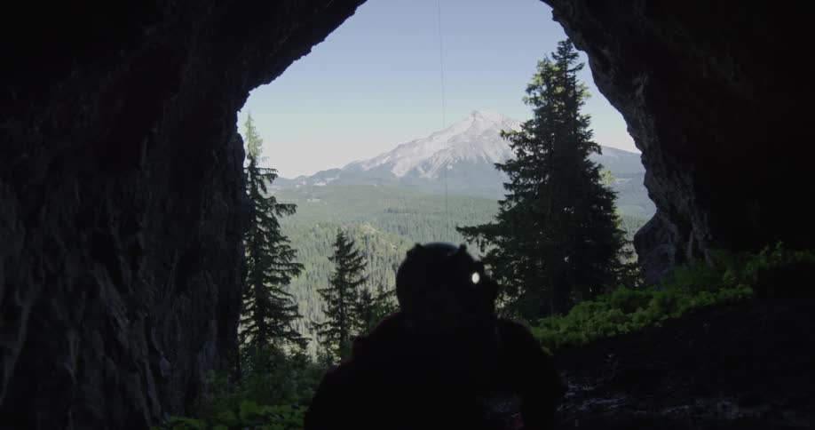 A man explores a dark cave with a headlamp