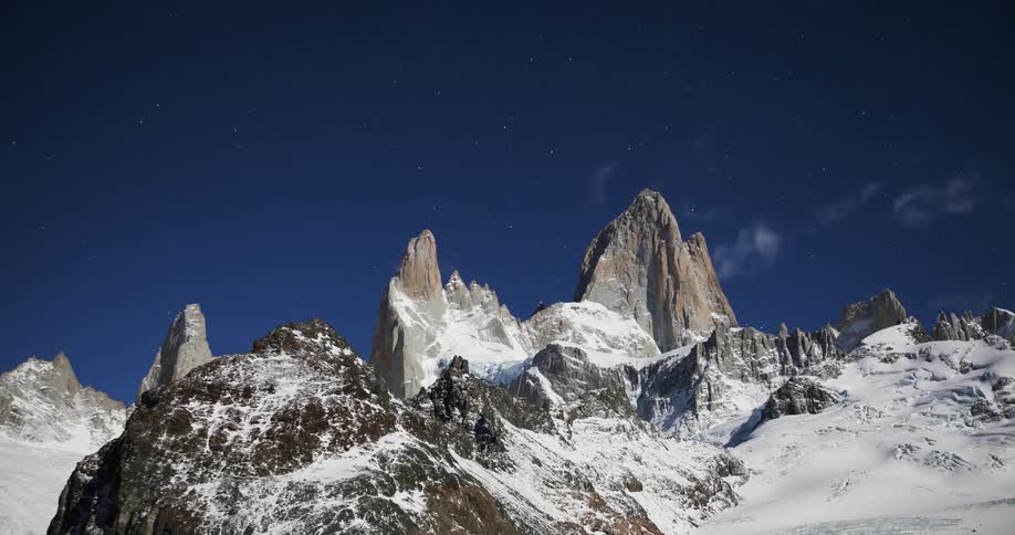 Clouds pass atop a snowy mountain