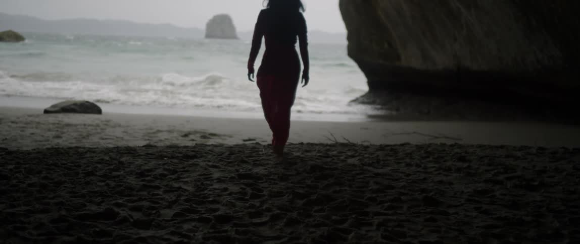 A woman walks on a beach on a windy day