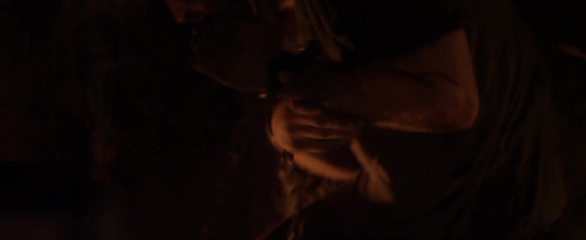 A man with chains on his arms tries to defend himself from punches in the dark