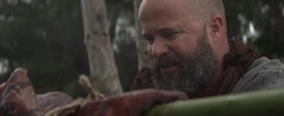 Bearded man eats something off of his knife