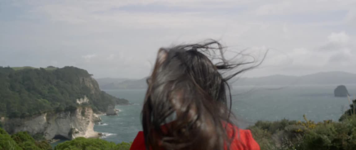 A woman walks on the coast on a windy day