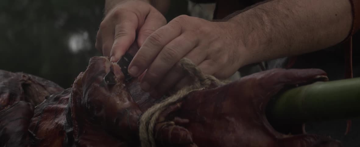 A man cuts a chunk of meat with a knife and takes a bite