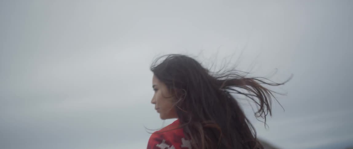 A woman walks on the beach on a cloudy day