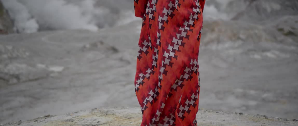 A woman stands outside on a rock on  windy day