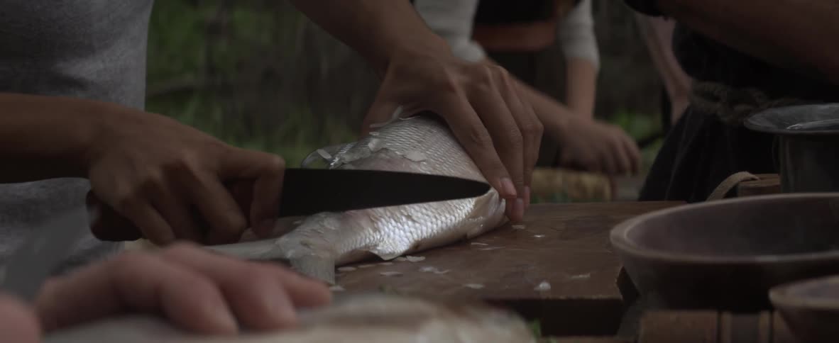 People are cutting up fish on a table