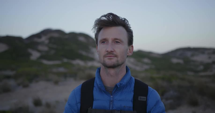 A hiker stands in the mountains on a breezy day