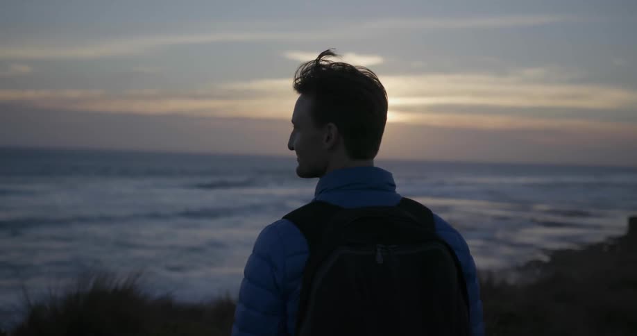 A man stands on a windy day by the shore