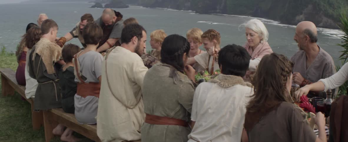 A large group of people dine outside on the coast
