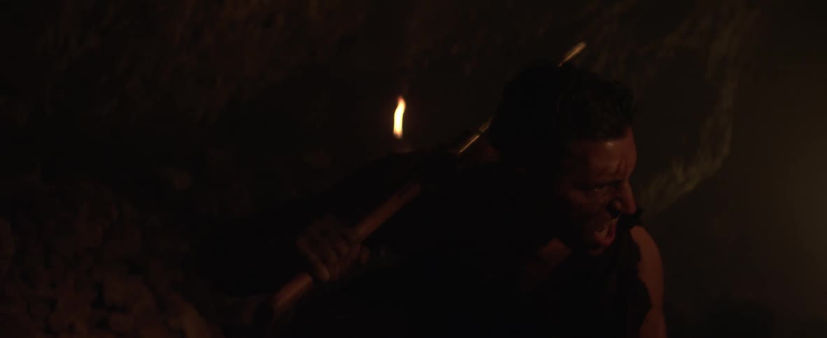 A man stalks someone with a knife in a cave