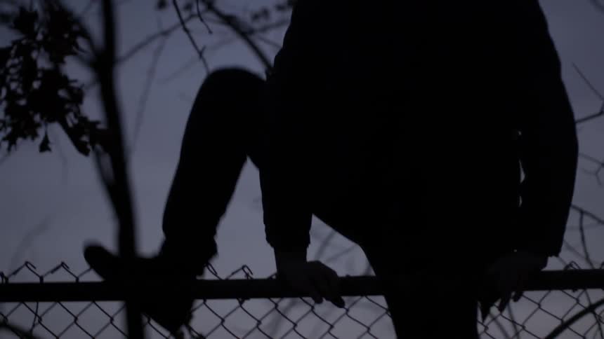 A man jumps up and over a fence