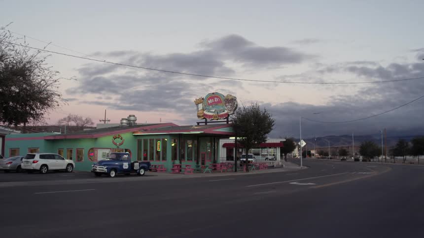 A restaurant is green and sitting across street