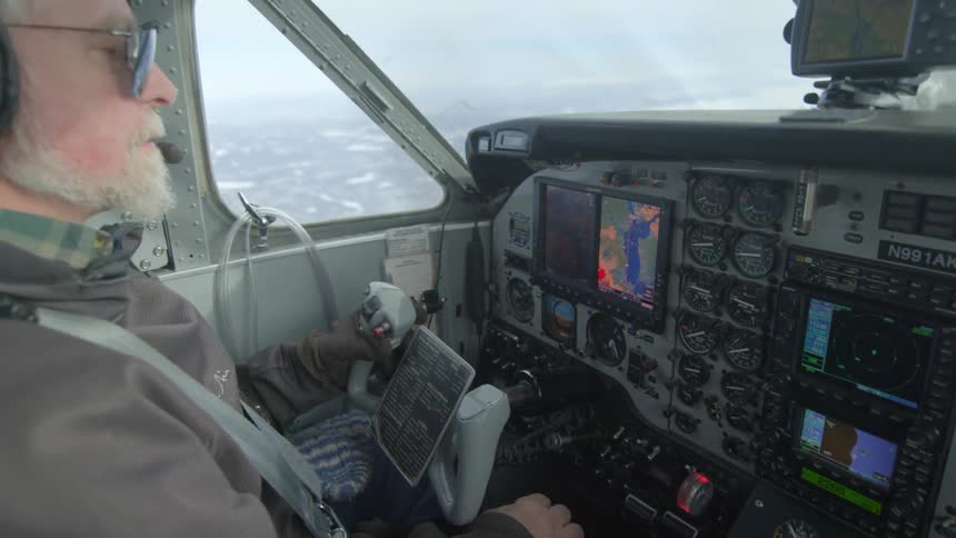 A pilot is flying over frozen water