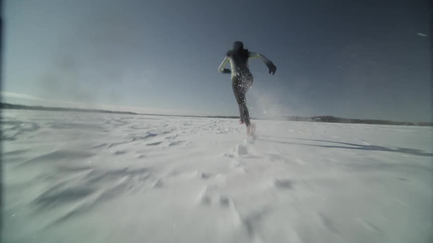 A woman is running across the ice and snow