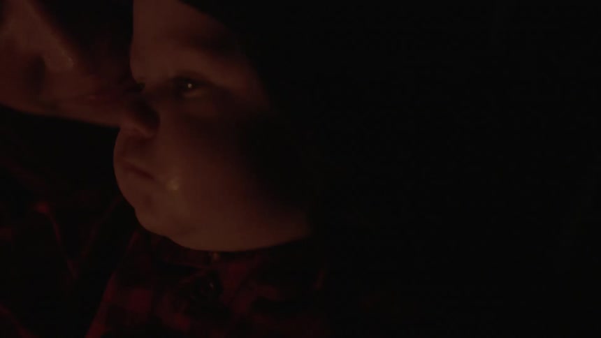 A woman and baby sitting next to a burning fire
