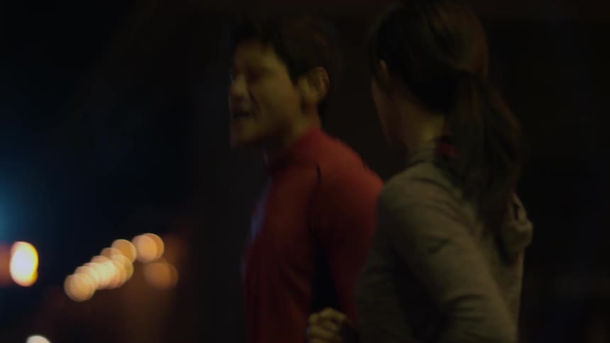 Two people jog outside at night
