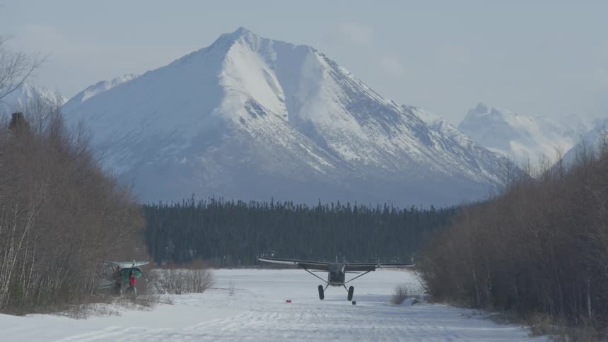Small airplane flying low and landing on a snowy ground
