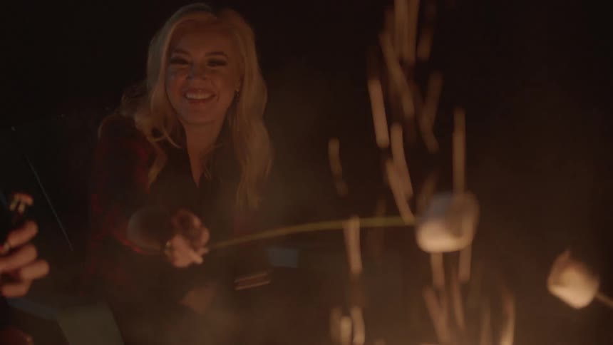 Woman holding a marshmallow over a campfire