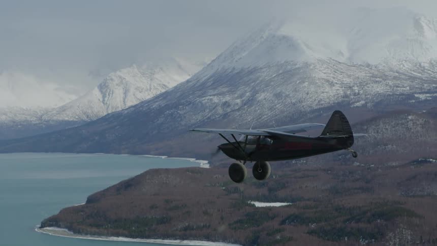 A small airplane flies over a mountain lake