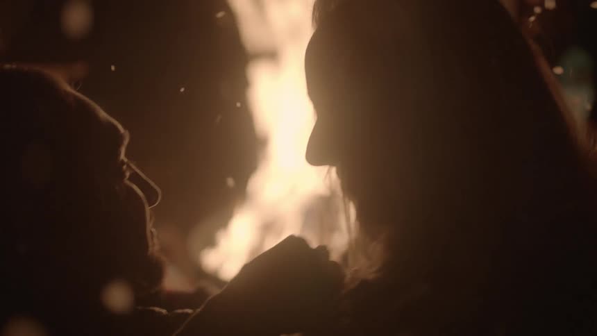 A man and woman get romantic in front of a fire