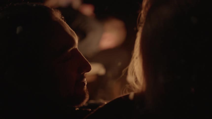 People talking by a large campfire at night