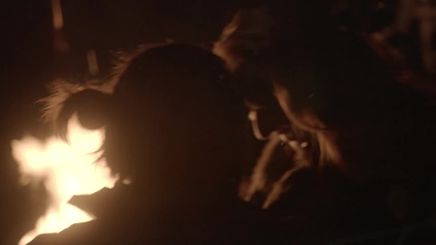 People sit next to a campfire at night