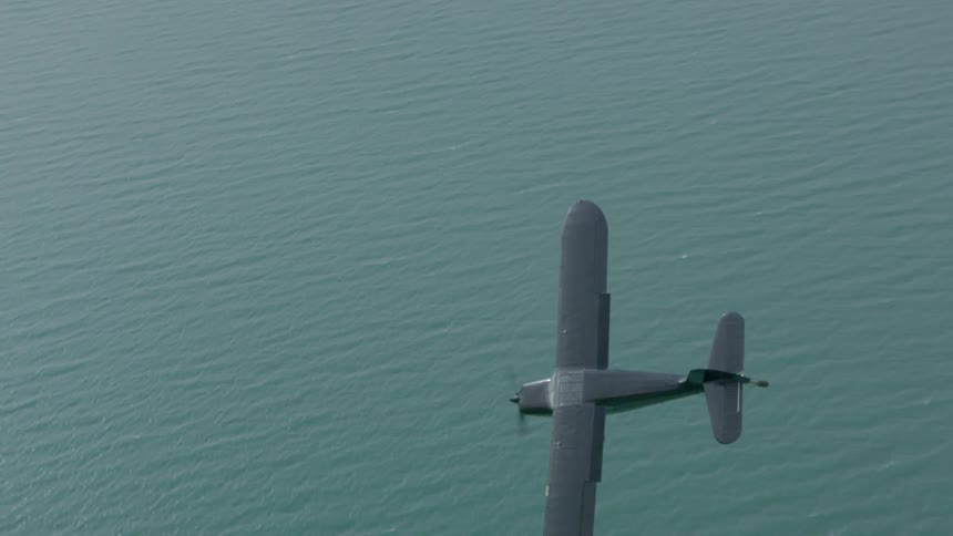 Aerial view of a small airplane flying over water
