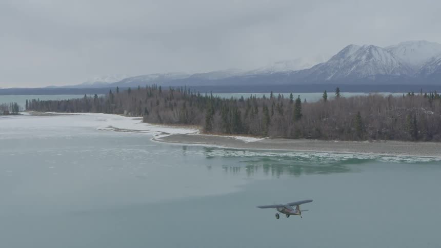 A plane is soaring over a lake in the country