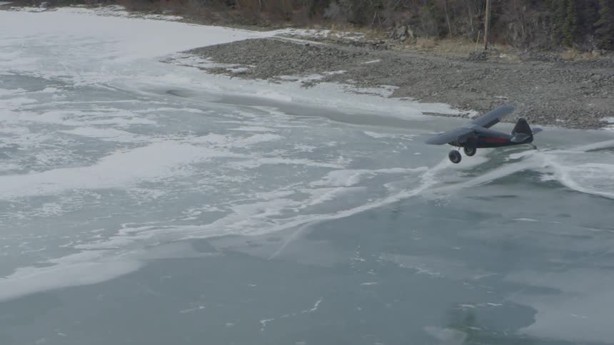 A small airplane flying over a frozen lake
