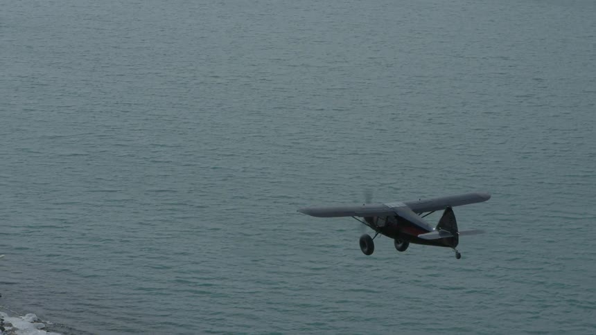 A plane is shown flying over a lake