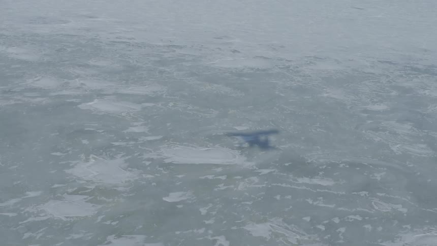 A plane is flying over a frozen lake