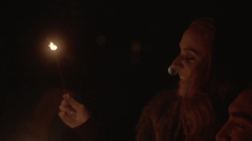 Man and woman holding sparklers outside at night