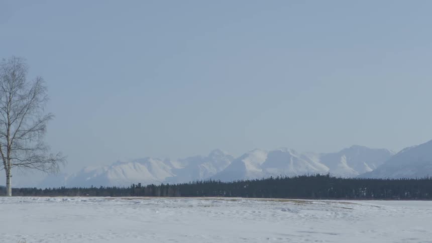 Large field filled with snow with mountains in the distance