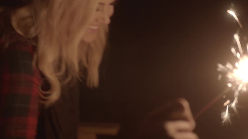 A man and woman laughing and holding burning sparklers