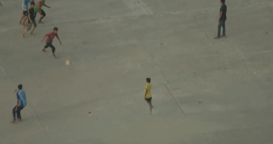 Children play soccer on a concrete plaza