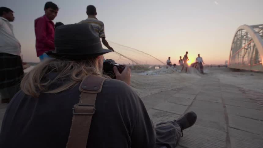 A person photographs people pulling a net