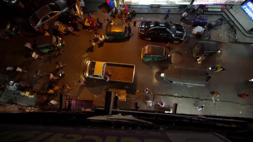 Pedestrians and commuters travel on a city street at night