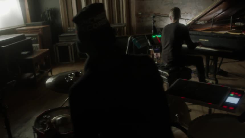 Person playing a piano while another plays the drums