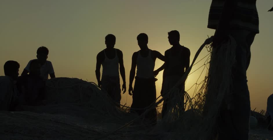 Group of people work on a large fishing net