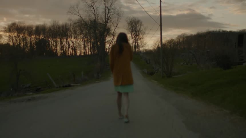 A woman is walking down a trail at dawn