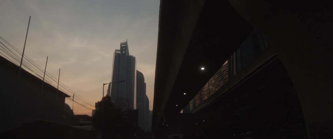 A vehicle drives beneath a city overpass at sunset