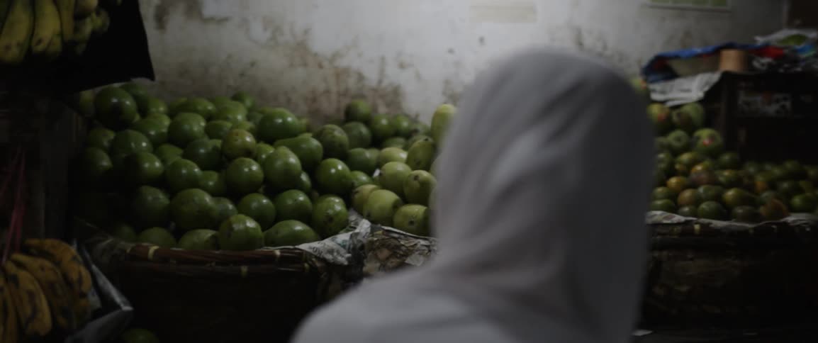 A person throws fruit into a market basket