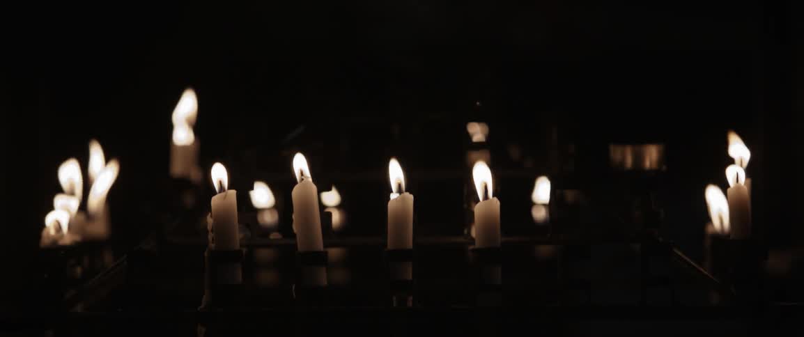 The candles flicker in the dark room