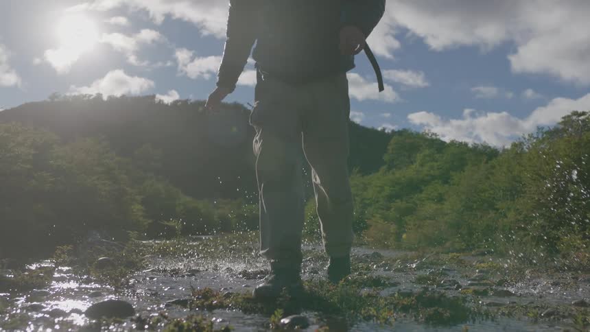 Hikers cross a stream in the mountains